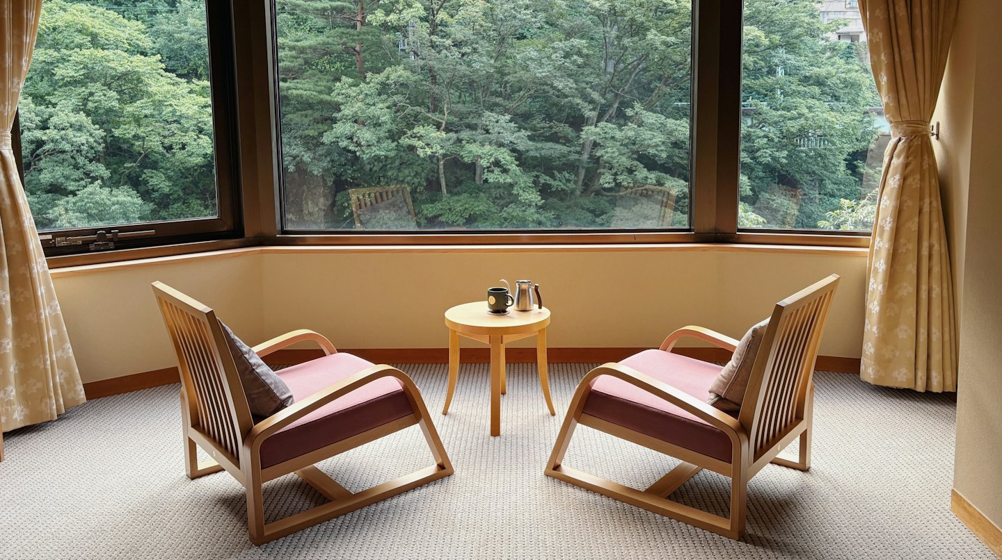 Dos sillas y una mesa frente a un bosque.